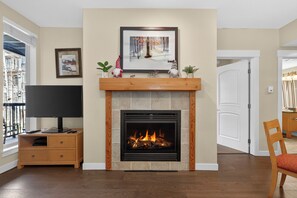 A fireplace with a TV on a wooden stand, a framed picture above it, and a door to the right.