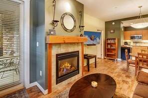 Un salon avec une cheminée, un plancher en bois, un coin repas et une cuisine.