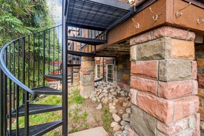 Eine Wendeltreppe mit Metallgeländern führt zu einem Steinhaus mit Backsteinfassade.