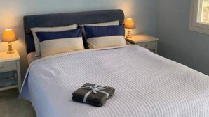 Quarto com uma cama, duas luminárias de cabeceira, uma janela e uma mesa de cabeceira.