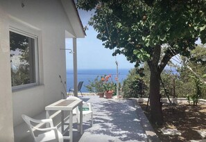 A patio with a table and chairs, a potted plant, and a view of the sea. - Villa - Sleeps 9 - Parking - Pool - Sea Views (Angon)