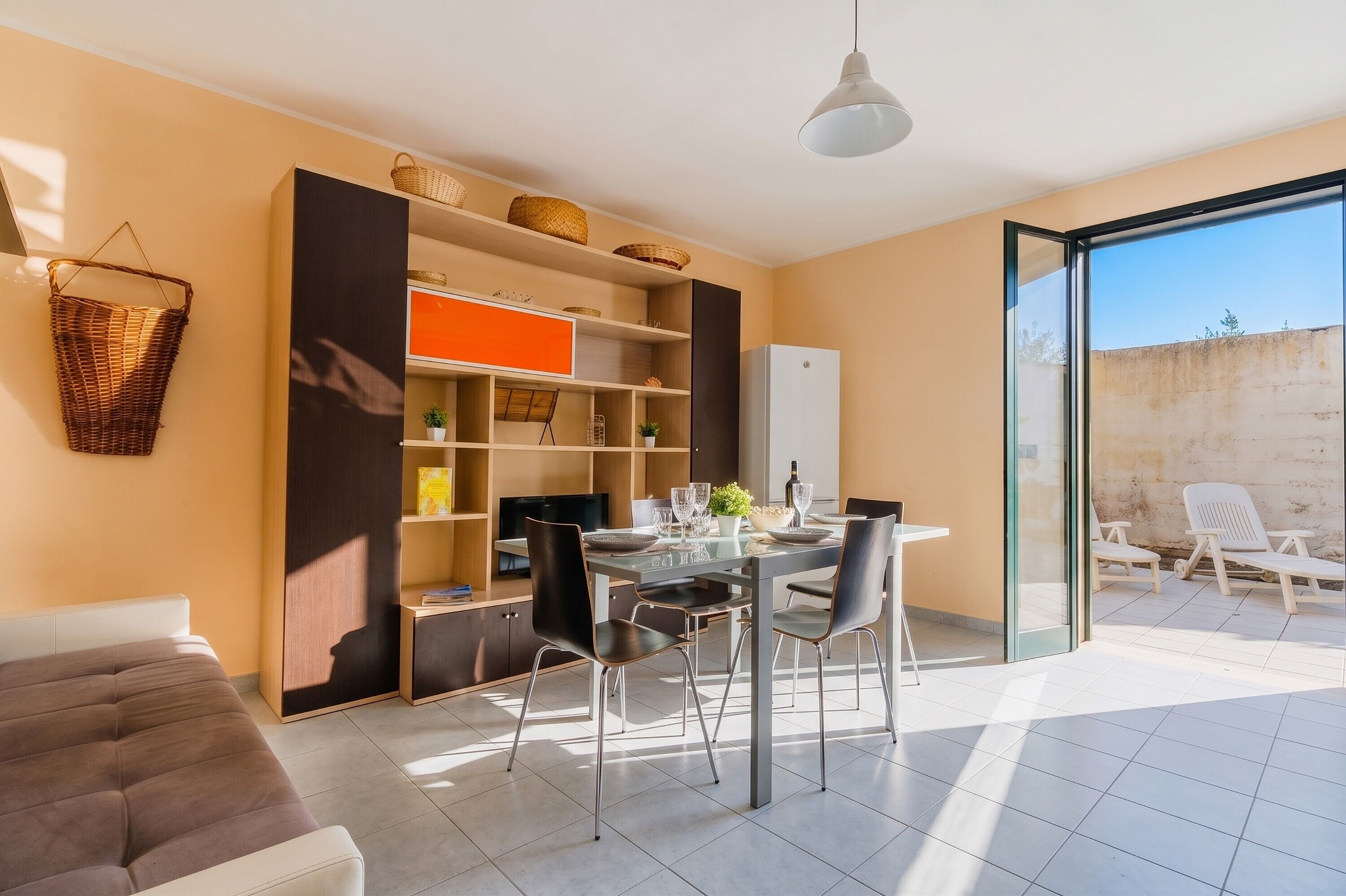 Uma sala de estar moderna com sofá, mesa de jantar, cadeiras e uma varanda com cadeiras.