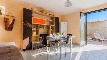 Uma sala de estar moderna com sofá, mesa de jantar, cadeiras e uma varanda com cadeiras.