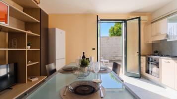 A modern kitchen with a dining area, a TV, and a view of the outdoors.