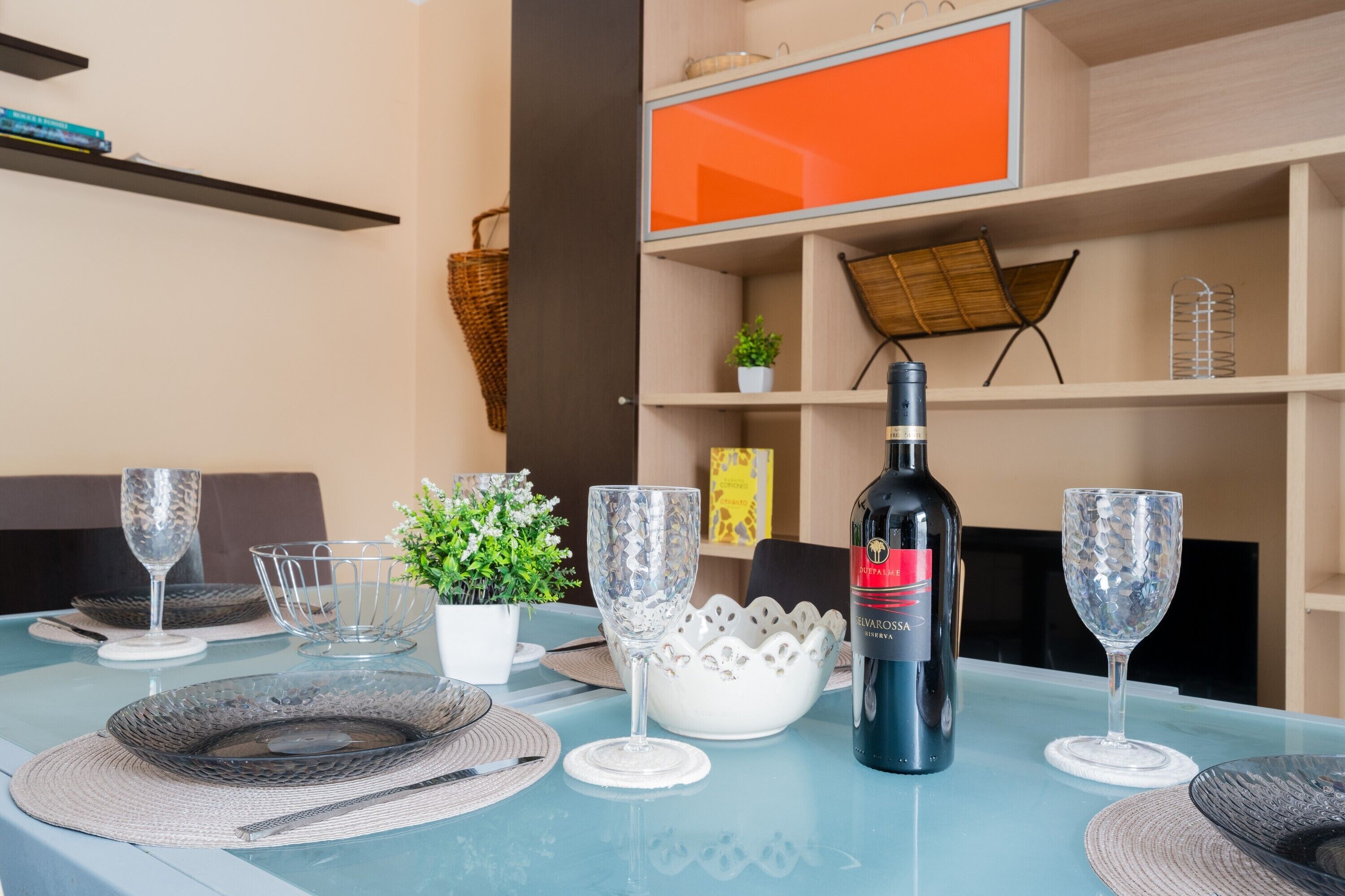 Mesa de jantar posta com taças de vinho, pratos e uma garrafa de vinho.