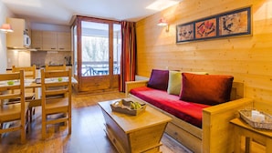 A cozy wooden interior with a sofa, dining table, chairs, and a kitchen area. - Inviting Mountain Studio in Savoie (Brides-les-Bains)