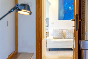 A room with a wooden door, a lamp, a bed with patterned pillows, and a painting on the wall. - Apartment 'Penthouse Villa Stefania' with Sea View, Wi-Fi and Air Conditioning (Lu Bagnu)