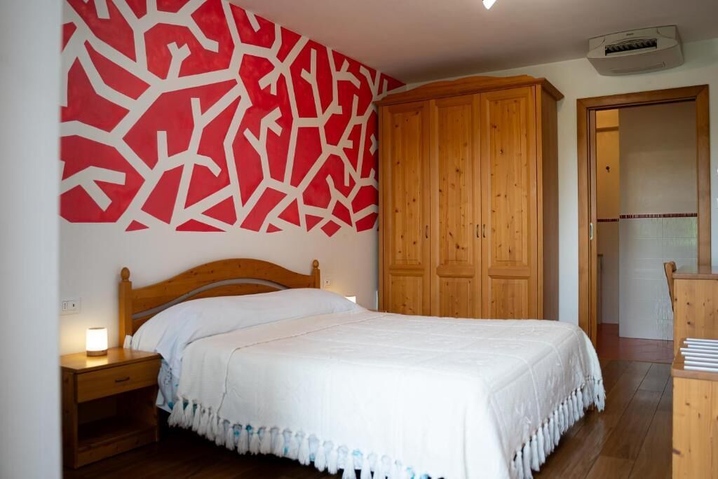 Une chambre à coucher avec un lit, une armoire en bois et une table de chevet avec une lampe.