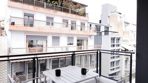 Un balcón con mesa y sillas, con vista a un paisaje urbano de edificios.
