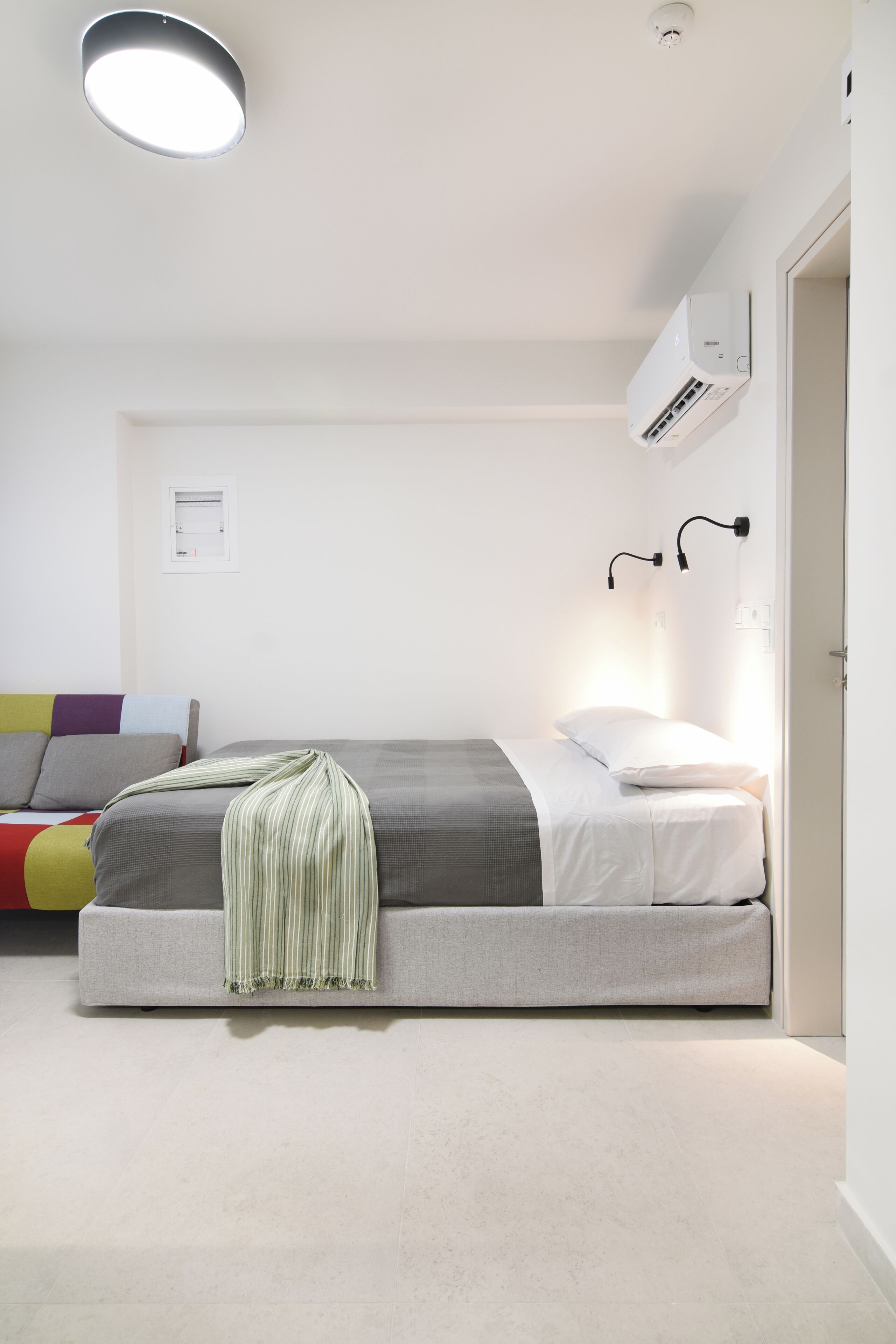 Una camera da letto con un letto, lampade sui comodini, un condizionatore e una porta.