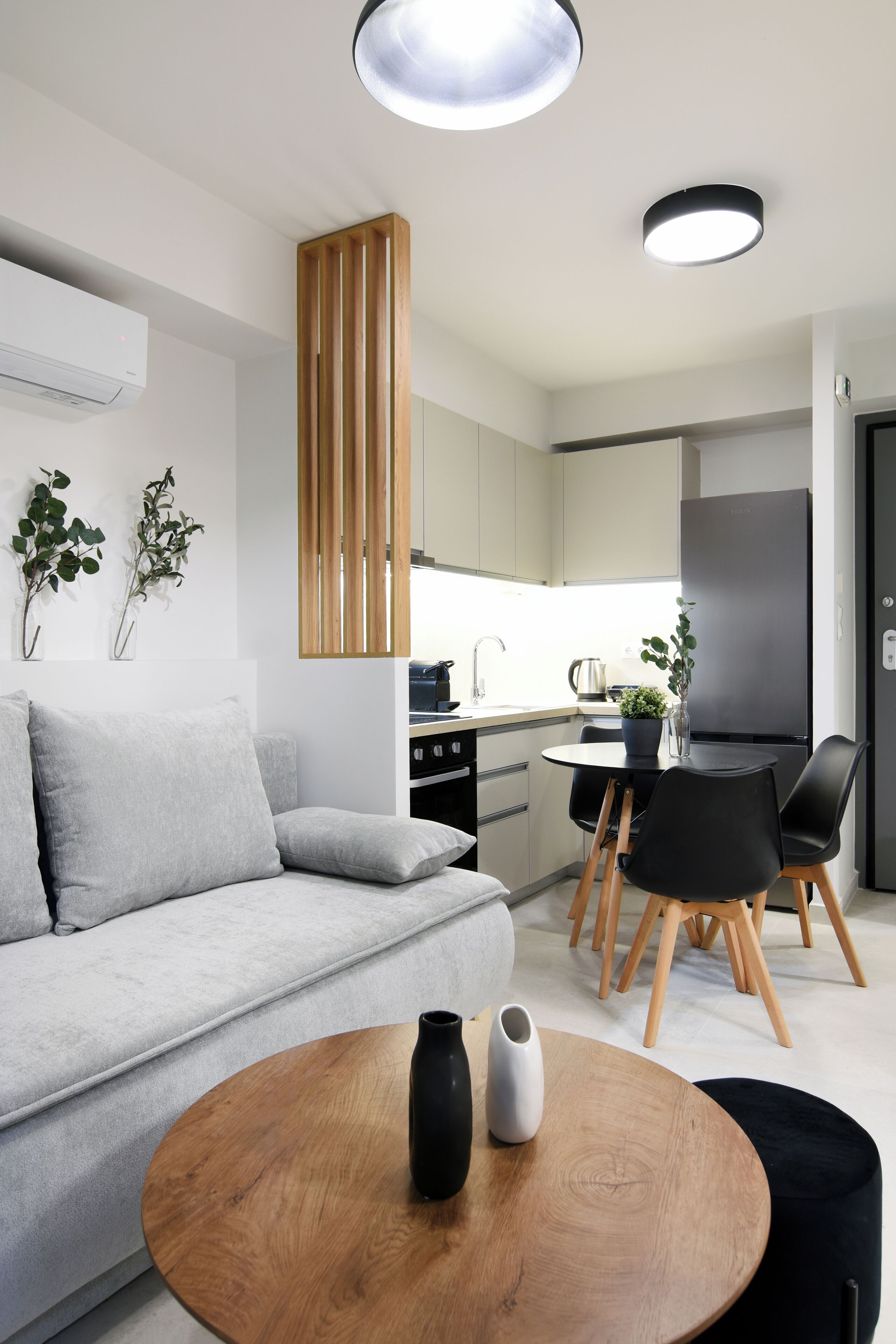 A modern living room with a sofa, a round wooden coffee table, and a dining area with a table and chairs.