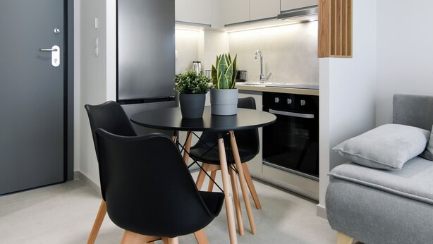 Una cocina moderna con zona de comedor, un sofá gris y una pared de madera decorativa.