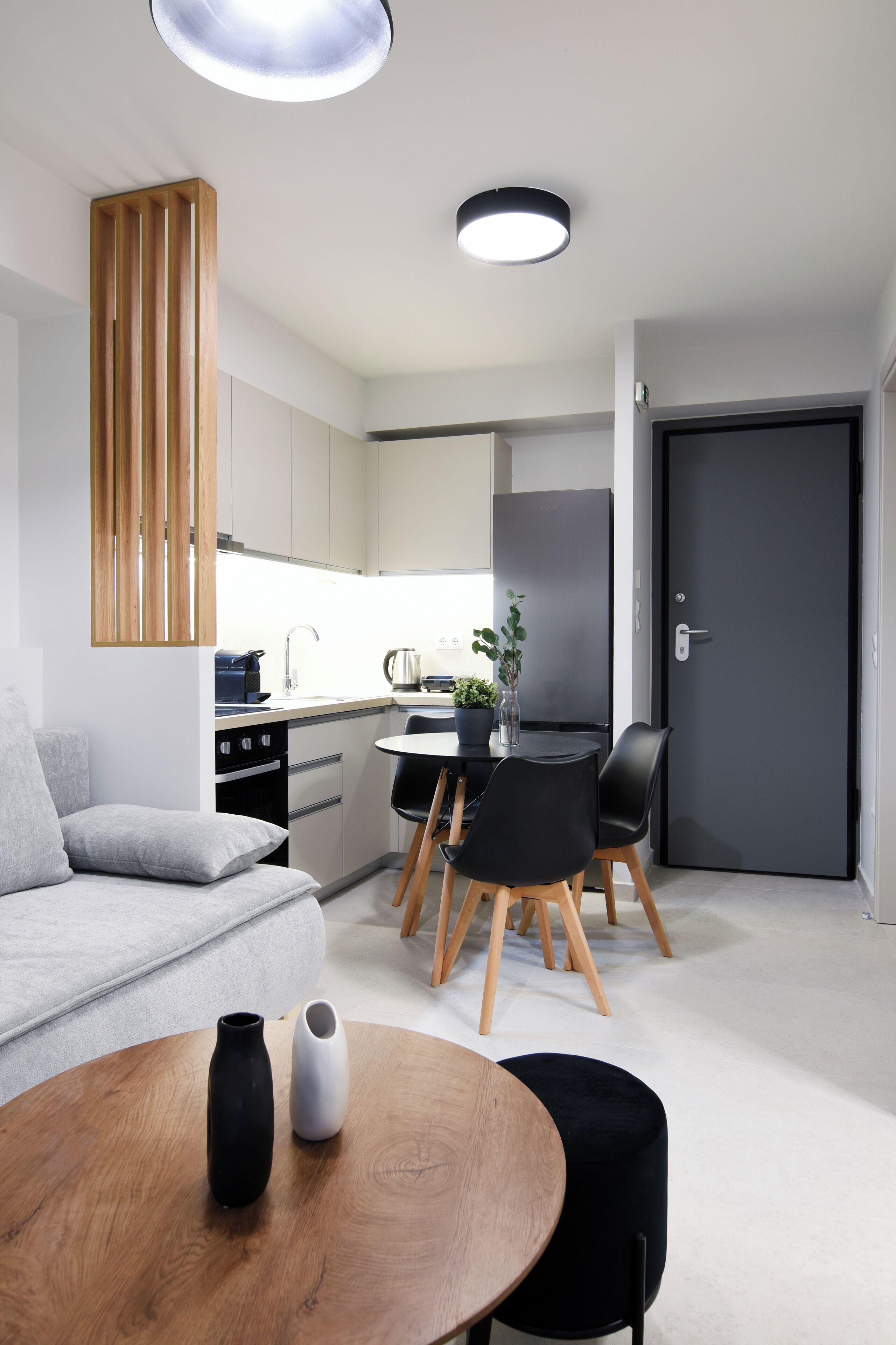 A modern kitchen with white cabinets, a black refrigerator, and a dining area with a round table and chairs.