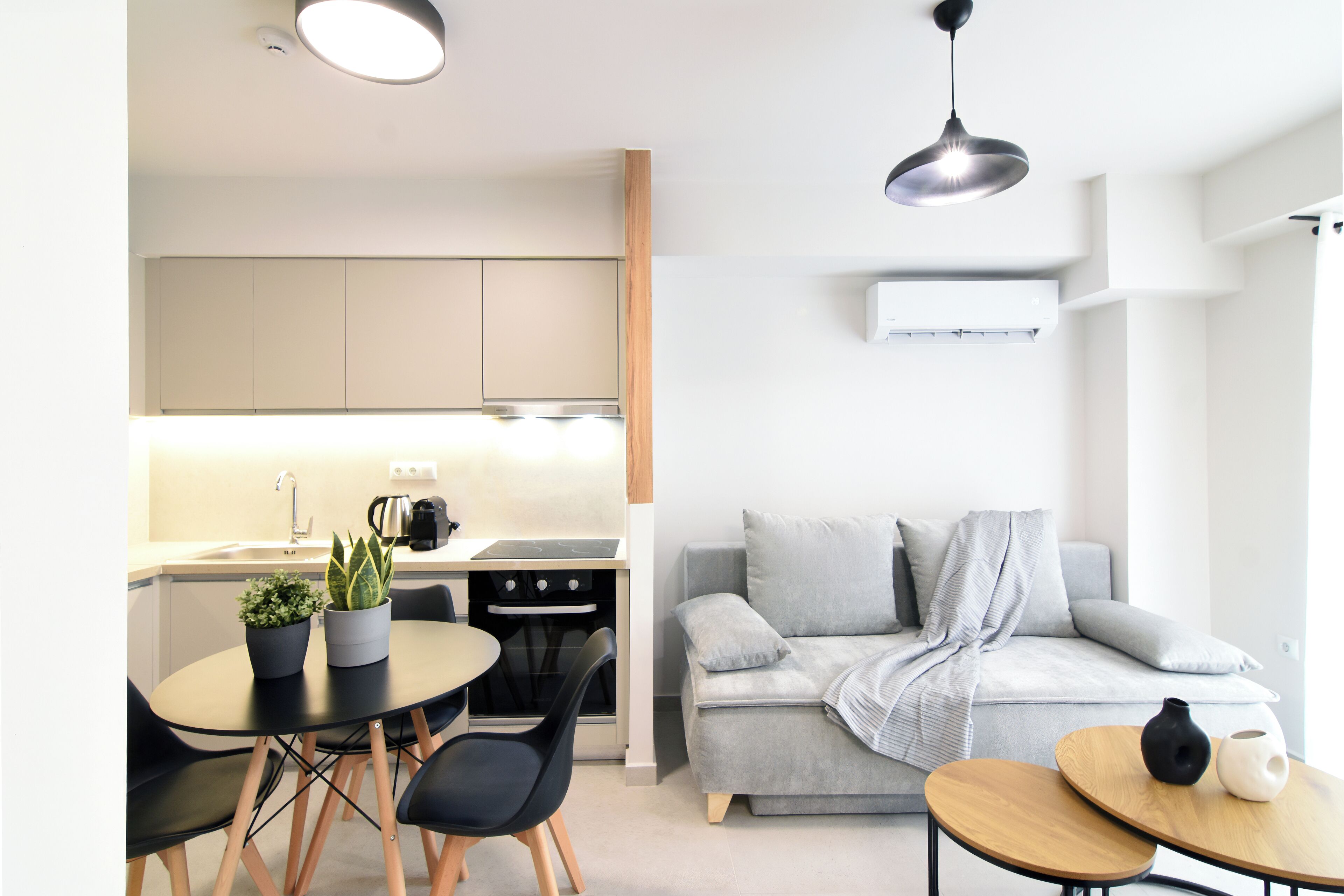 A modern kitchen with a dining area, a sofa, and a small table with a vase.
