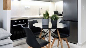 Una cocina moderna con comedor, que incluye una mesa redonda, sillas negras, un refrigerador y una estufa.