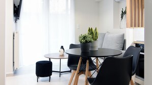 Una cocina moderna con zona de comedor, que incluye una mesa redonda, sillas negras, un pequeño otoman negro y una planta en maceta.