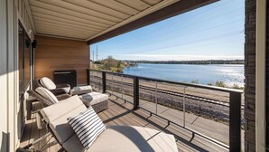 Una terrazza coperta con poltrone relax e vista su un lago e dei binari ferroviari.