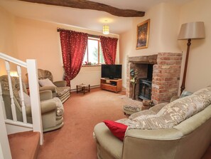 A living room with a fireplace, a television, and a staircase. - The Retreat (Wellington)