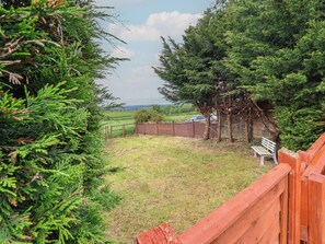 A fenced backyard with a bench, trees, and a view of the countryside. - The Retreat (Wellington)