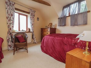 A bedroom with a bed, a chair, a dresser, a window with curtains, and a lamp. - The Retreat (Wellington)