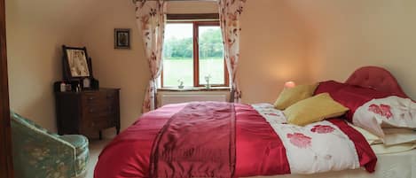 A bedroom with a bed, a dresser, a window with curtains, and a lamp.