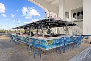 Eine Bar am Wasser mit überdachtem Sitzbereich und blauen Stühlen.