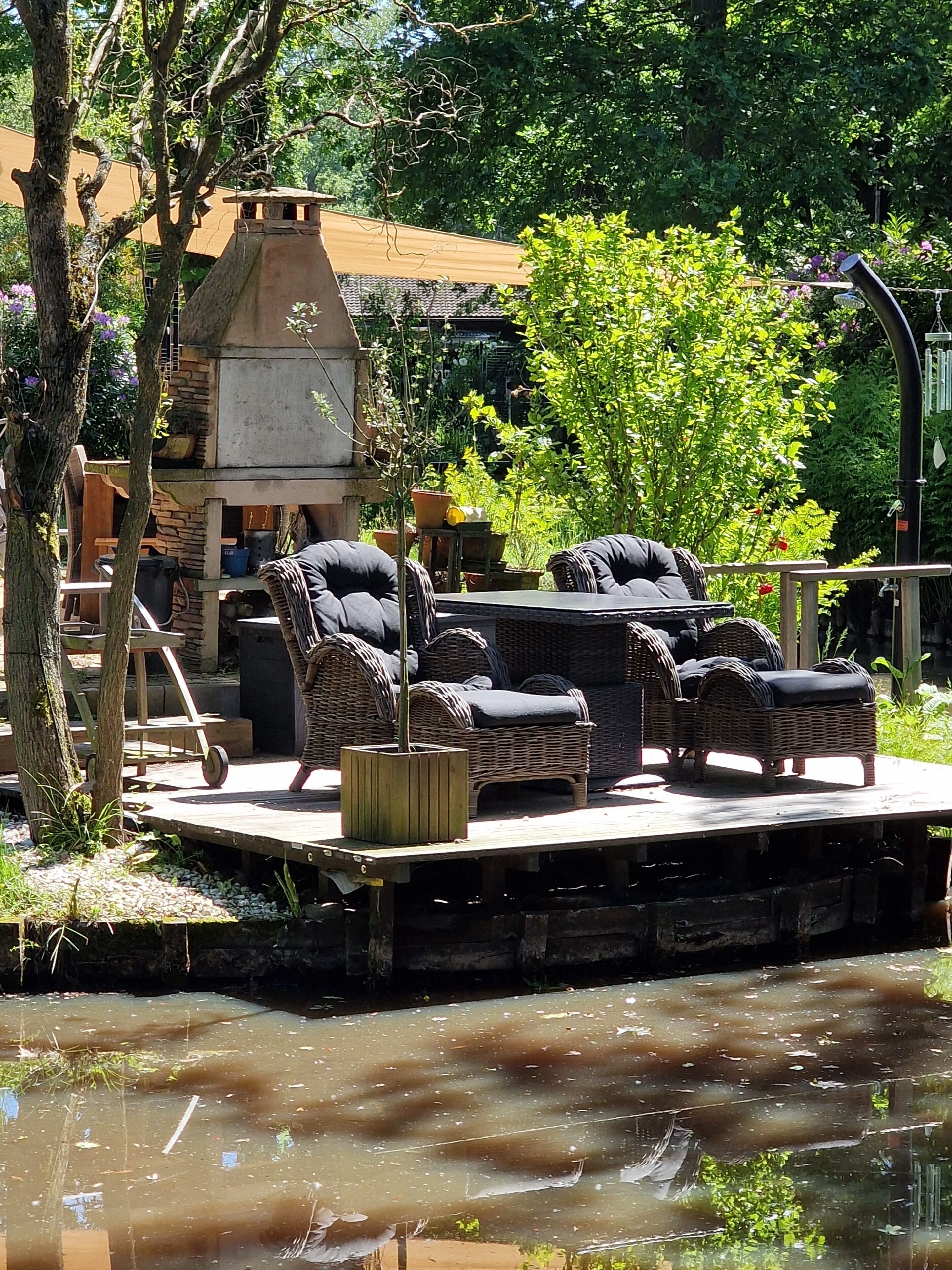 Une terrasse extérieure aménagée avec des meubles en osier, un barbecue et un élément décoratif aquatique.