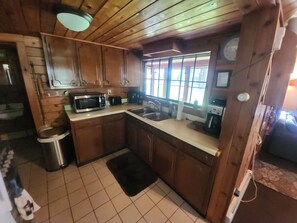 A compact kitchen with wooden cabinets, a microwave, a toaster, and a sink.