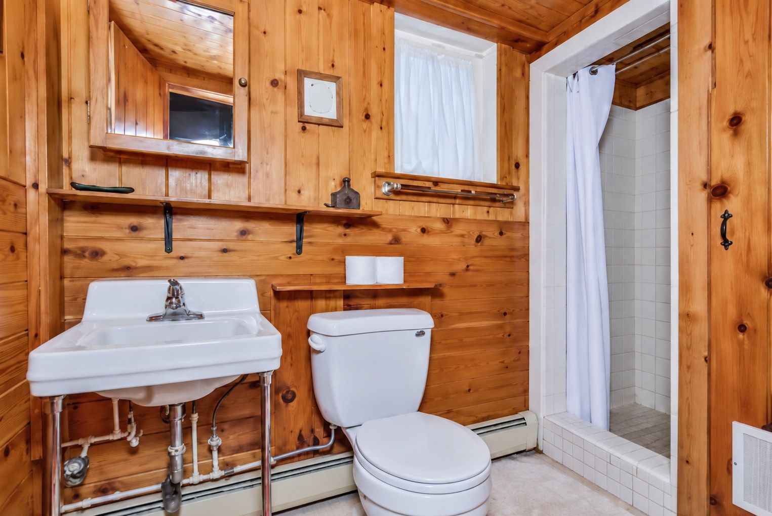 Rustic cabin bathroom with warm wood finishes and tiled walk-in shower