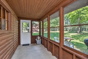 Screened porch with peaceful yard views, outdoor seating, and cabin charm