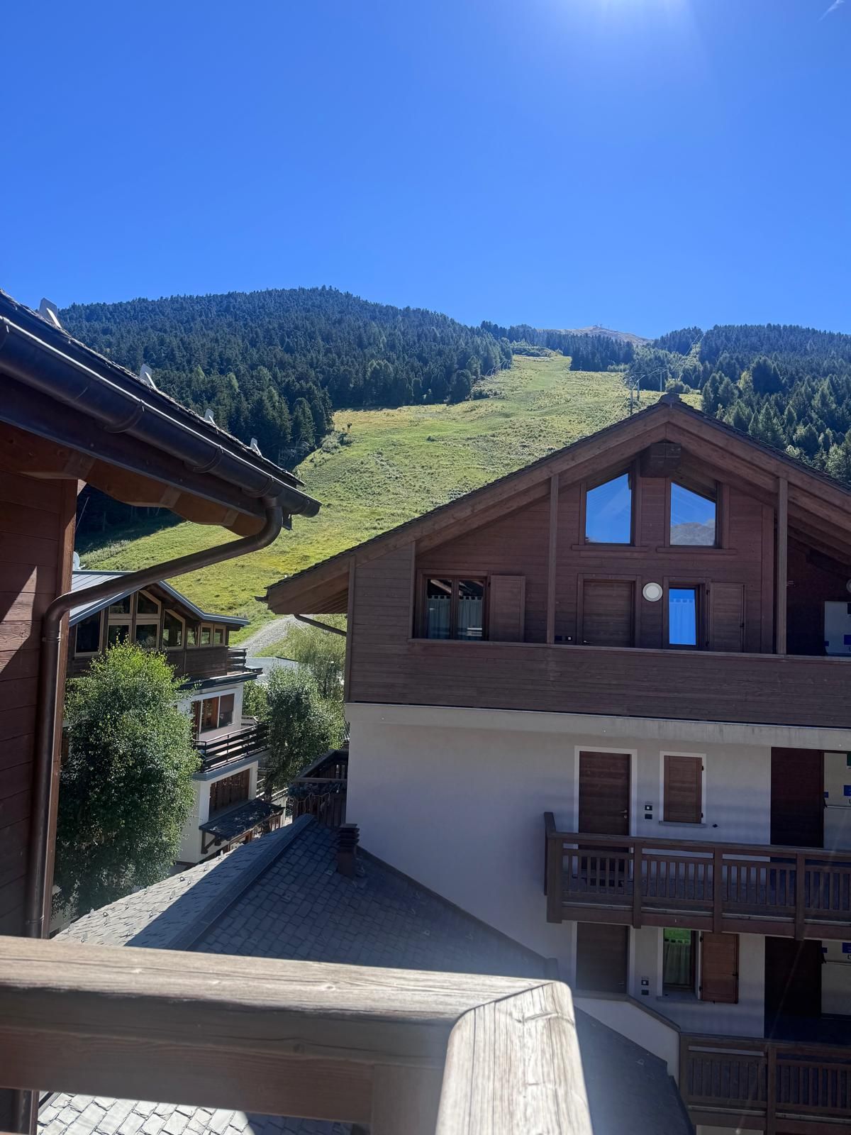 A multi-story wooden building with balconies, set against a mountainous backdrop.