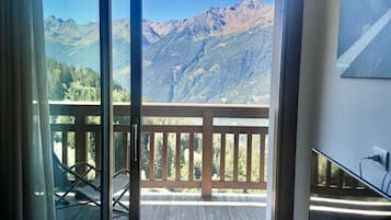 Una habitación con un amplio ventanal corredero que da a un balcón con vistas a la montaña.