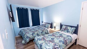 Una camera da letto con due letti, un comodino e una finestra con tende.