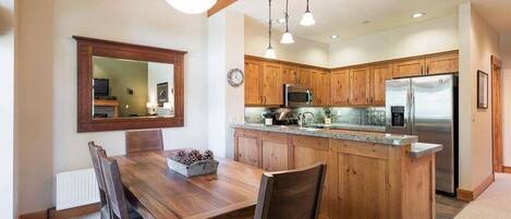 A kitchen with wooden cabinets, a stainless steel refrigerator, and a granite countertop.