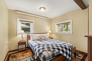 Ein Schlafzimmer mit einem Bett, zwei Nachttischlampen, einem Fenster und einer Deckenleuchte.