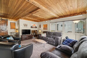 Ein Wohnzimmer mit Holzboden, einem Fernseher, einem Sofa und einem Couchtisch.