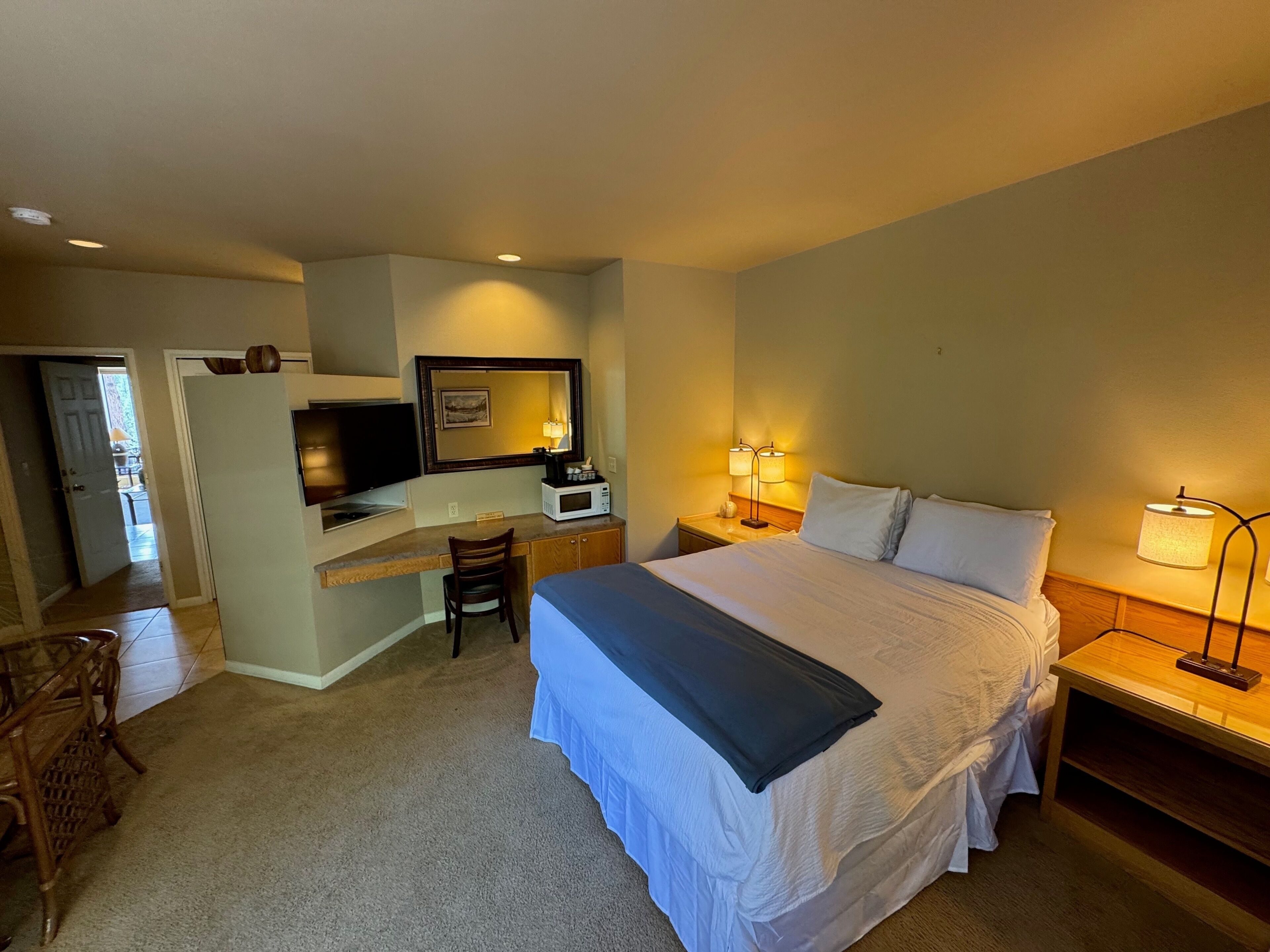 A hotel room with a bed, desk, chair, television, and two bedside lamps.