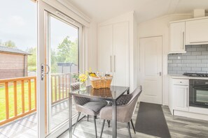 A modern kitchen with white cabinets, a built-in oven, and a glass dining table with chairs. - Host & Stay | Hazel Retreat (Felton)