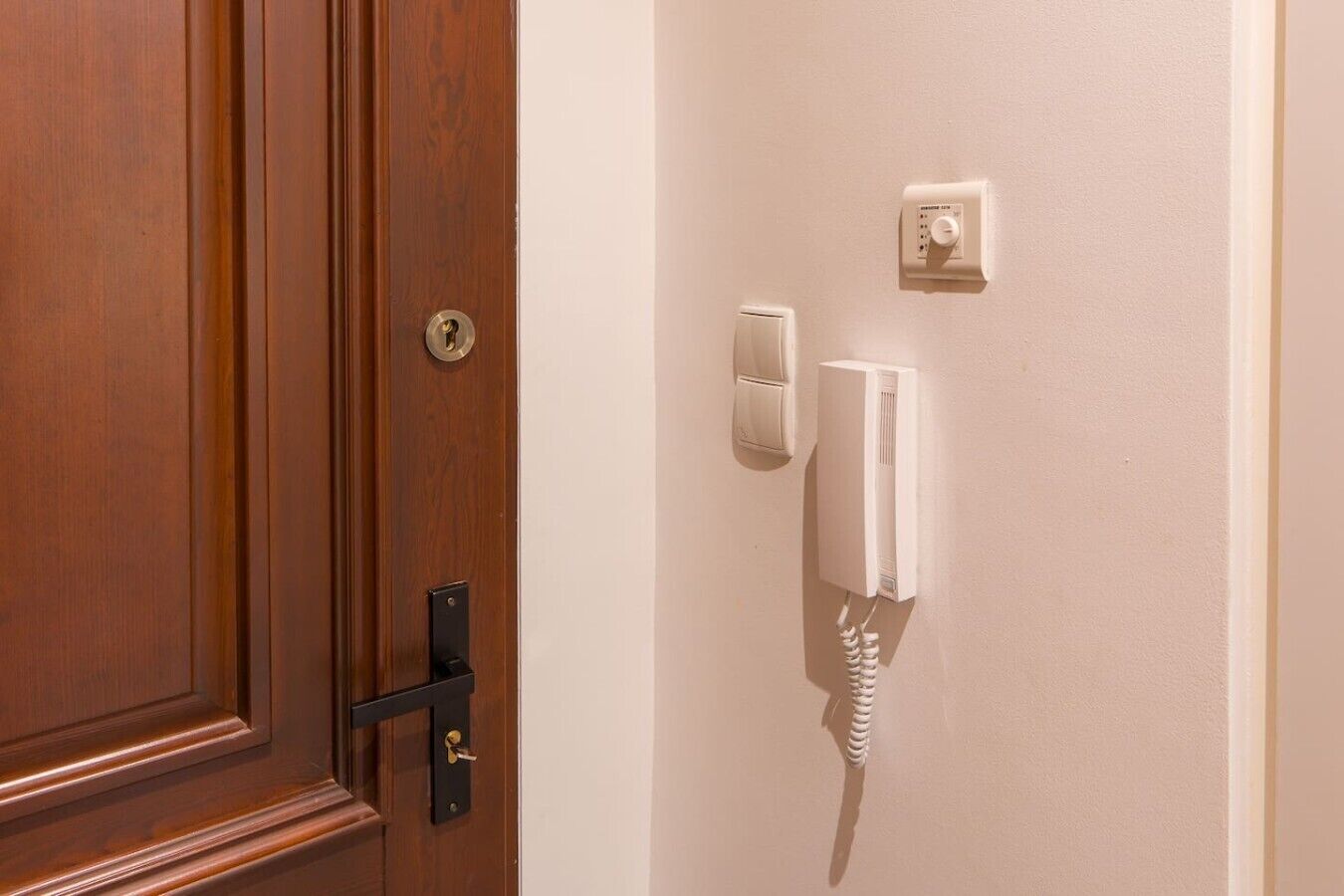 A wooden door with a lock and a wall-mounted telephone.