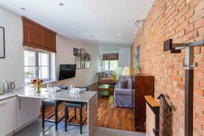 A modern kitchen with a dining area, a TV mounted on the wall, and a brick wall. - Garbary Studio - Old Town, Top Location - by Rentujemy (Poznań)