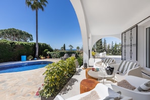 A poolside area with outdoor seating, a view of the sea, and a well-maintained garden. - Elegant Villa With Pool Terrace in Marbella (Marbella)