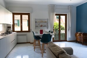 A modern kitchen with white cabinets, a dining table set for four, and a sofa in the living area. - Green Terrace Santa Margherita by Wonderful Italy (Santa Margherita Ligure)