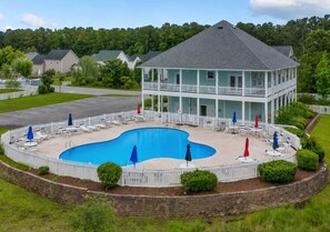Ein zweigeschossiges Gebäude mit Swimmingpool, umgeben von einem weißen Zaun und mit einer überdachten Terrasse.