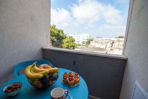 Ein Balkon mit Tisch, auf dem sich eine Obstschale, eine Tasse und Cupcakes befinden.