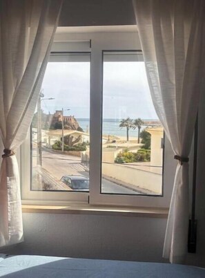 A room with a large window, curtains, and a bed. - Beach Front + Castle and sea view Home in Heart of Ferragudo (Ferragudo)