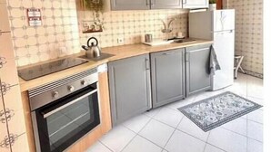 Une cuisine avec des meubles de couleur grise, une cuisinière, un évier et un réfrigérateur.