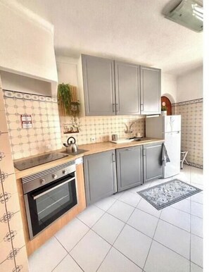 A kitchen with grey cabinets, a stove, a sink, and a refrigerator. - Beach Front + Castle and sea view Home in Heart of Ferragudo (Ferragudo)
