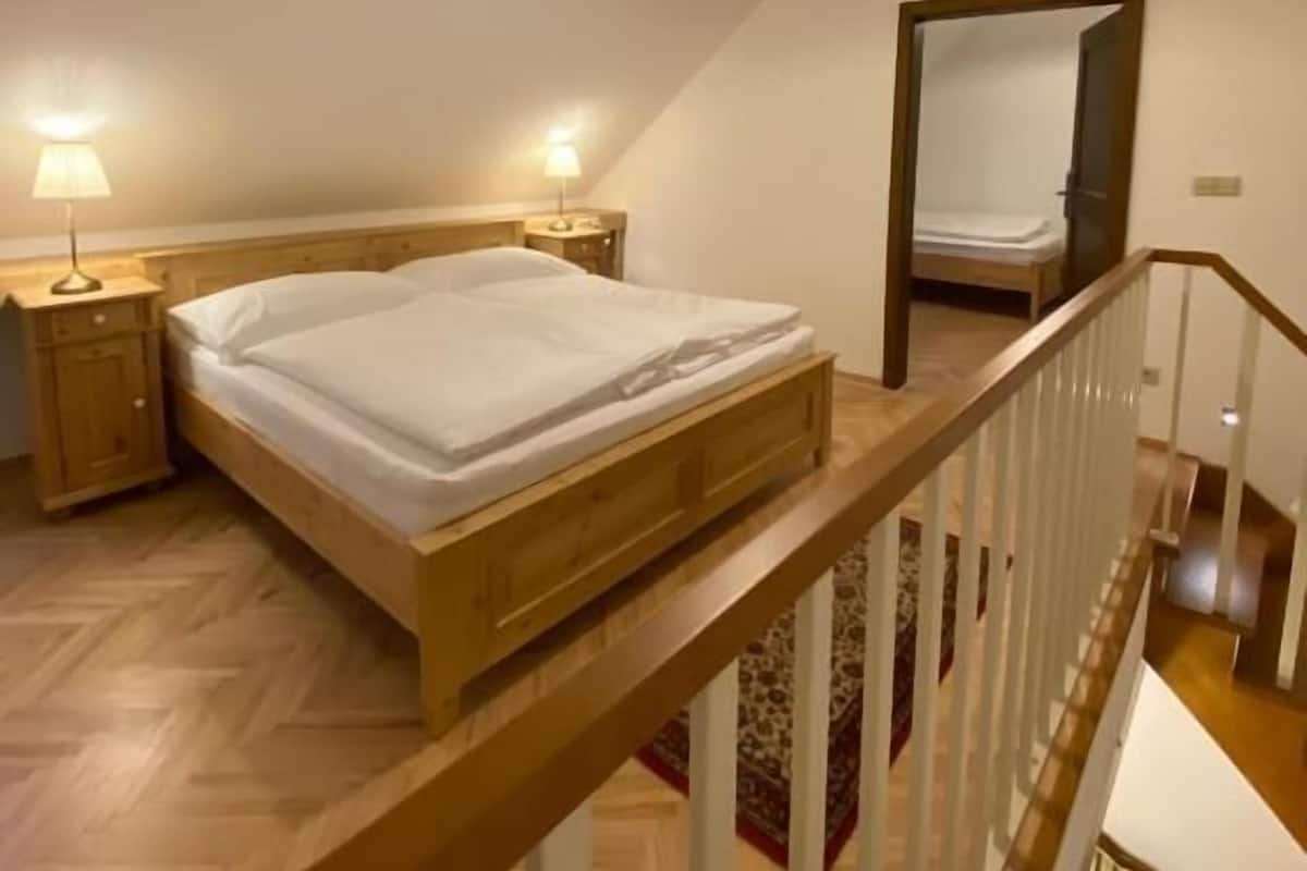 A bedroom with a wooden bed, a nightstand, a lamp, and a mirror.