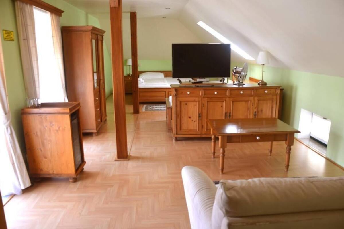A room with a bed, a TV, wooden furniture, and a window.