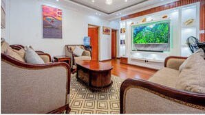 A living room with a large flat-screen TV, a coffee table, and seating area with sofas and chairs. - Kivulini luxurious and cozy apartment (Thika)